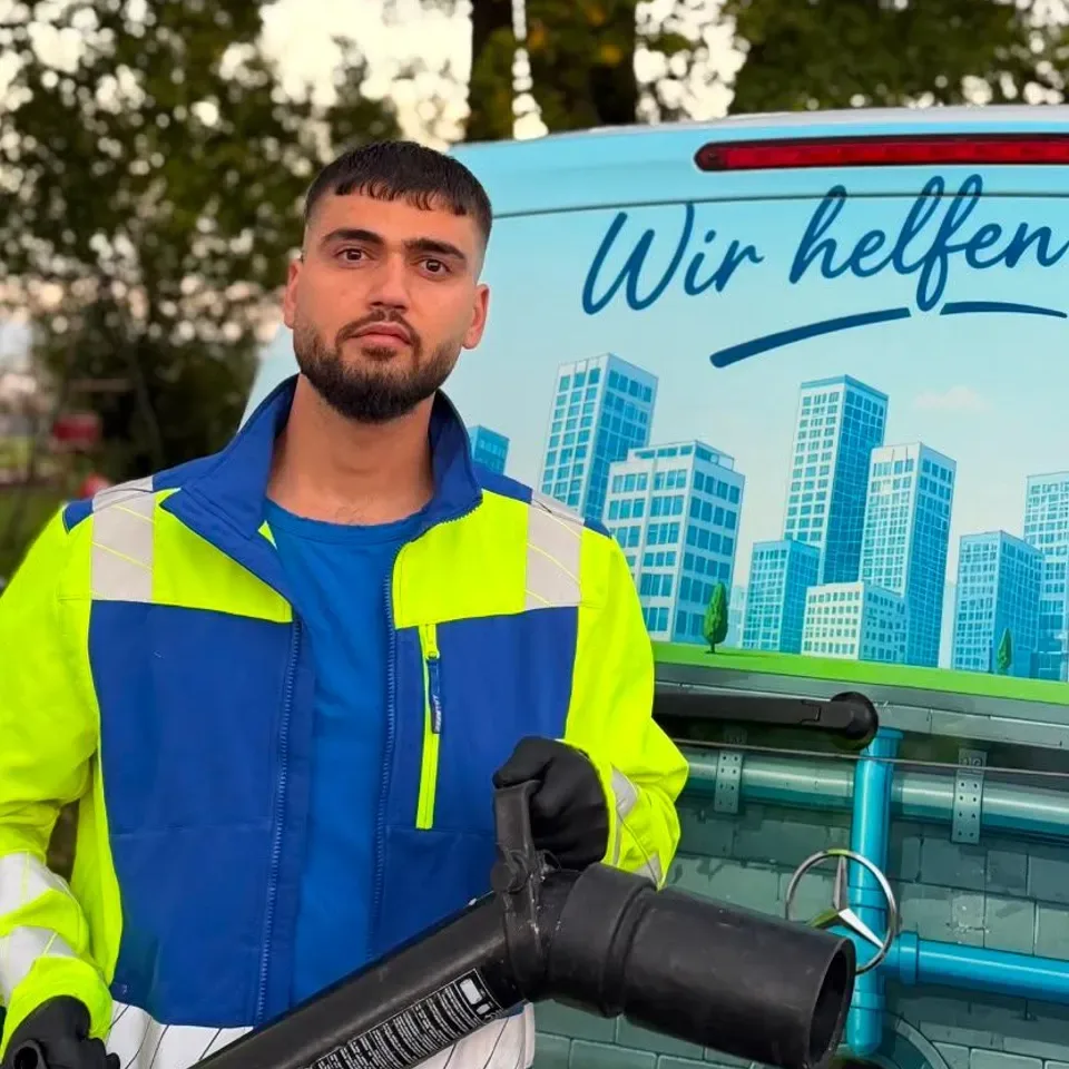 Techniker in Warnjacke mit dickem Schlauch vor dem Einsatzwagen