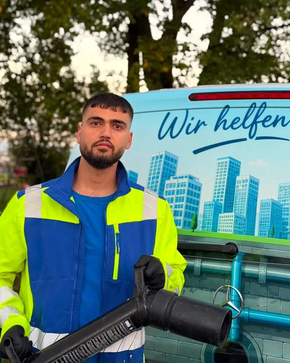 Techniker in Warnjacke mit Spülgerät vor dem Einsatzwagen
